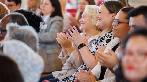 Nahaufnahme des Publikums. Sie lächeln und klatschen.