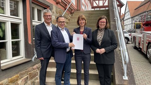 Der Kreistagsvorsitzende des Landkreises Kassel, Andreas Güttler, Immenhausens Bürgermeister Lars Obermann, Ministerin Heike Hofmann und Staatssekretärin Manuela Strube stehen zum Foto aufgestellt vor einer Treppe.