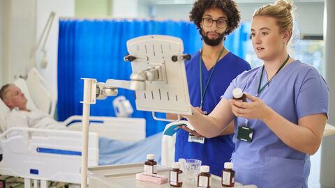 Krankenzimmer, Pflegekraft kontrolliert Medikamente am Rechner