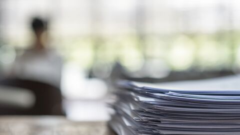 Ein Büro, im Vordergrund ist ein Papierstapel zu sehen