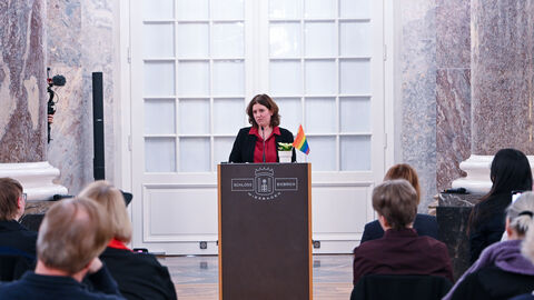 Frau hält Rede. Publikum hört zu.