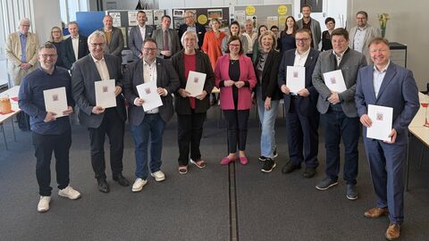 Personen stehen zusammen und halten Förderbescheide in Händen.