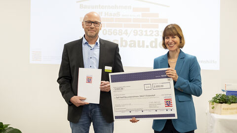 Preisverleihung Landespreis 2024 Sozialministerin Hofmann überreicht einem Herrn einen Scheck.