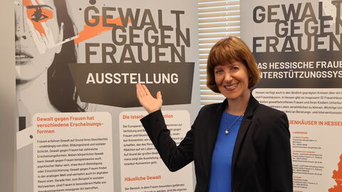 Sozialministerin Hofmann steht vor einem Aufsteller der Ausstellung "Gewalt gegen Frauen"