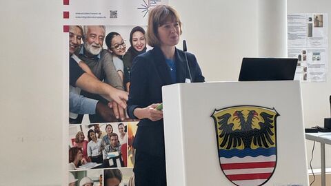 Integrationskonferenz Frau steht an Pult.