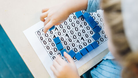 Kind spielt mir einem Blatt auf dem 1 und 0 sind.