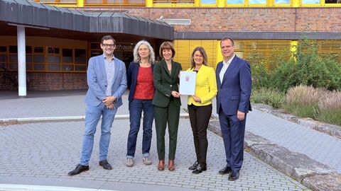 Fünf Personen stehen nebeneinander vor einem Gebäude.