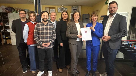 Mehrere Menschen stehen zusammen und halten Förderbescheid.