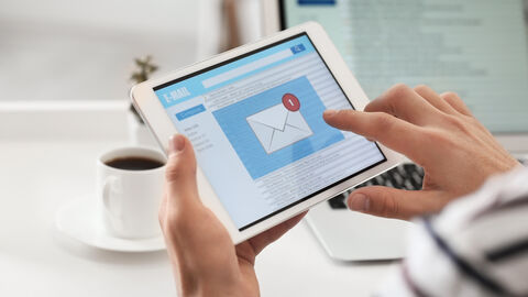 Newsletter Hände halten ein Tablet welches Informationen anzeigt