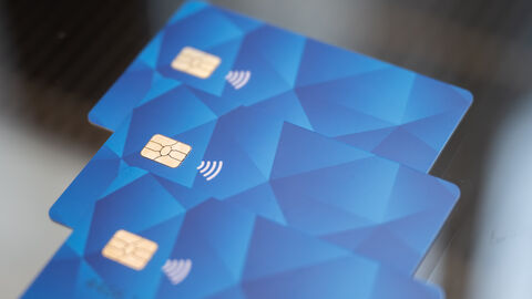 Bezahlkarte Drei blaue Geldkarten liegen übereinander auf einem Glastisch.