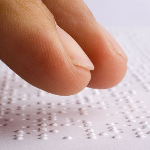 Mit Braille verfasster Text wird von Fingern ertastet Mit Braille verfasster Text wird von Fingern ertastet