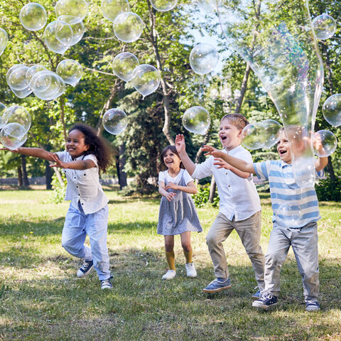 Mehrere Kinder spielen mit Seifenblasen Mehrere Kinder spielen mit Seifenblasen